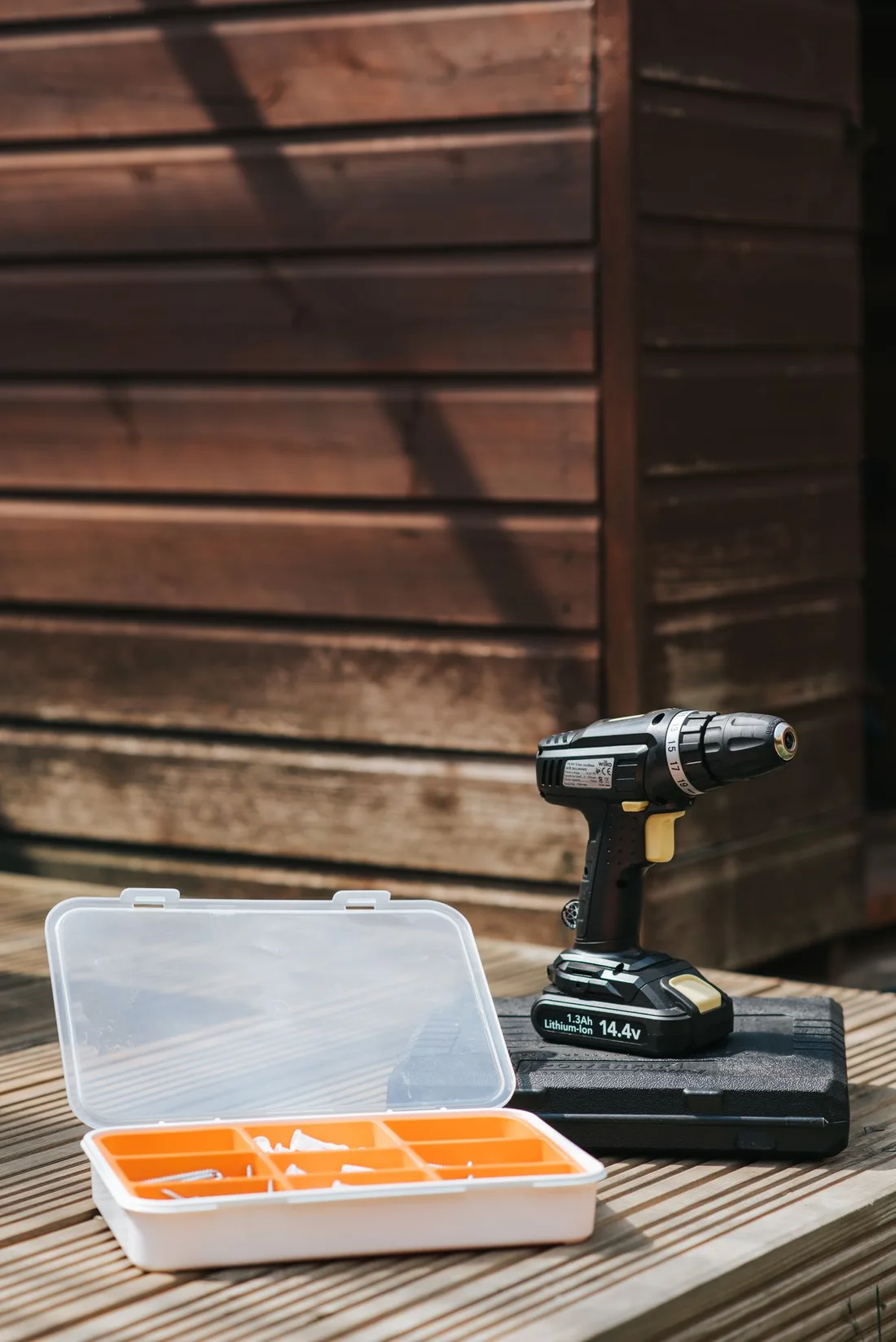 Cordless drill and organized tool accessories on a clean wooden surface