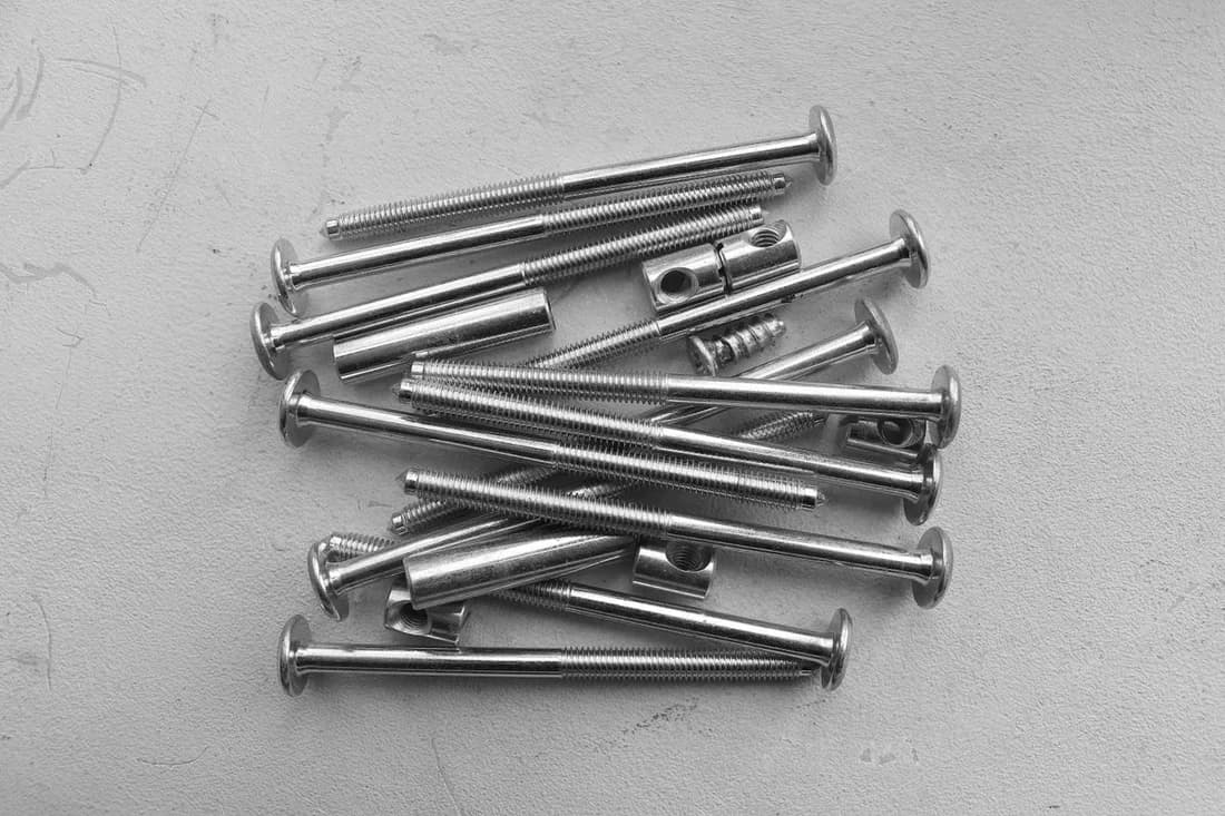Silver metal nails with visible heads and shafts on a white work surface