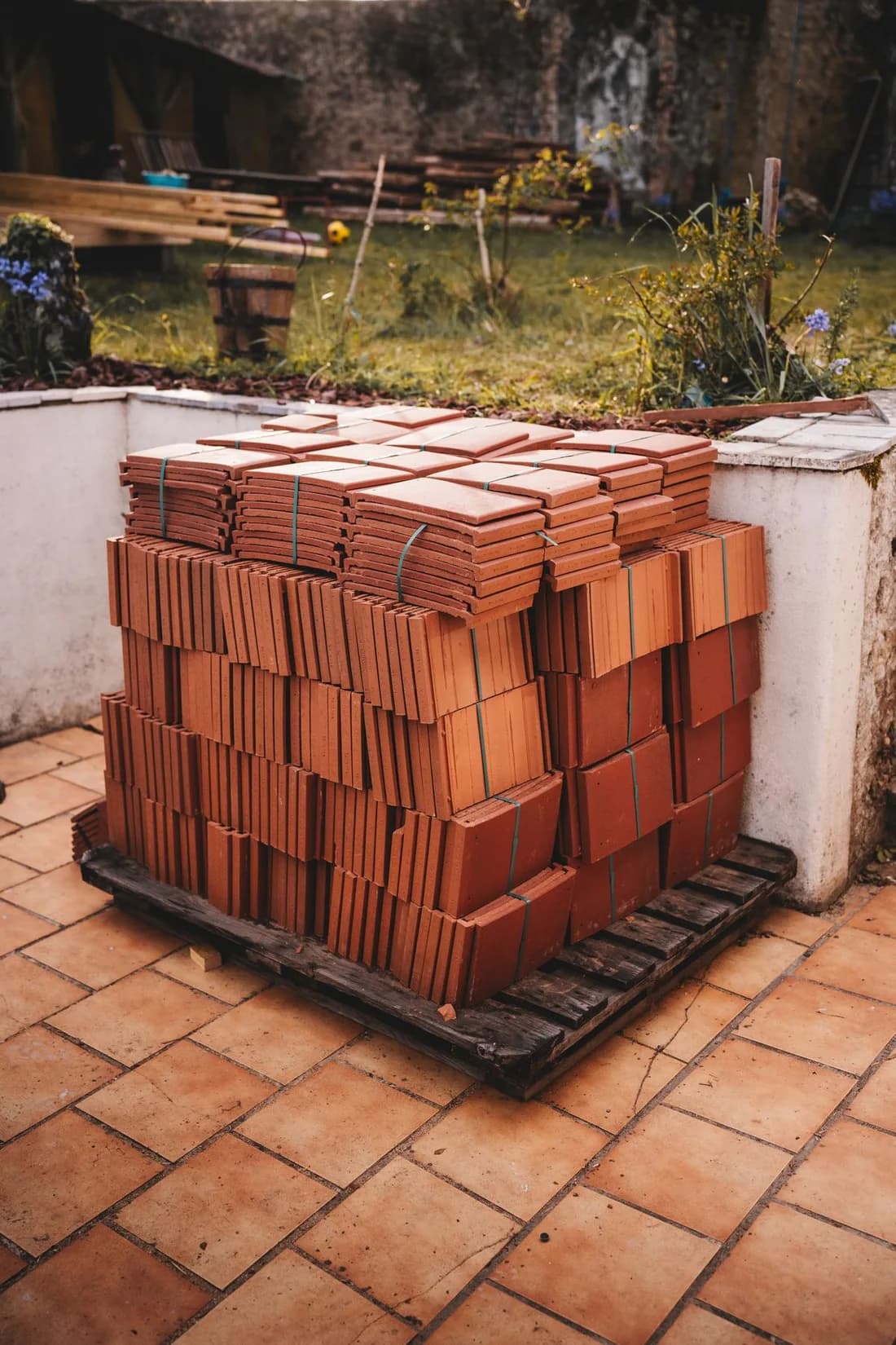 Terracotta roof tiles stacked on a pallet outdoors in natural daylight