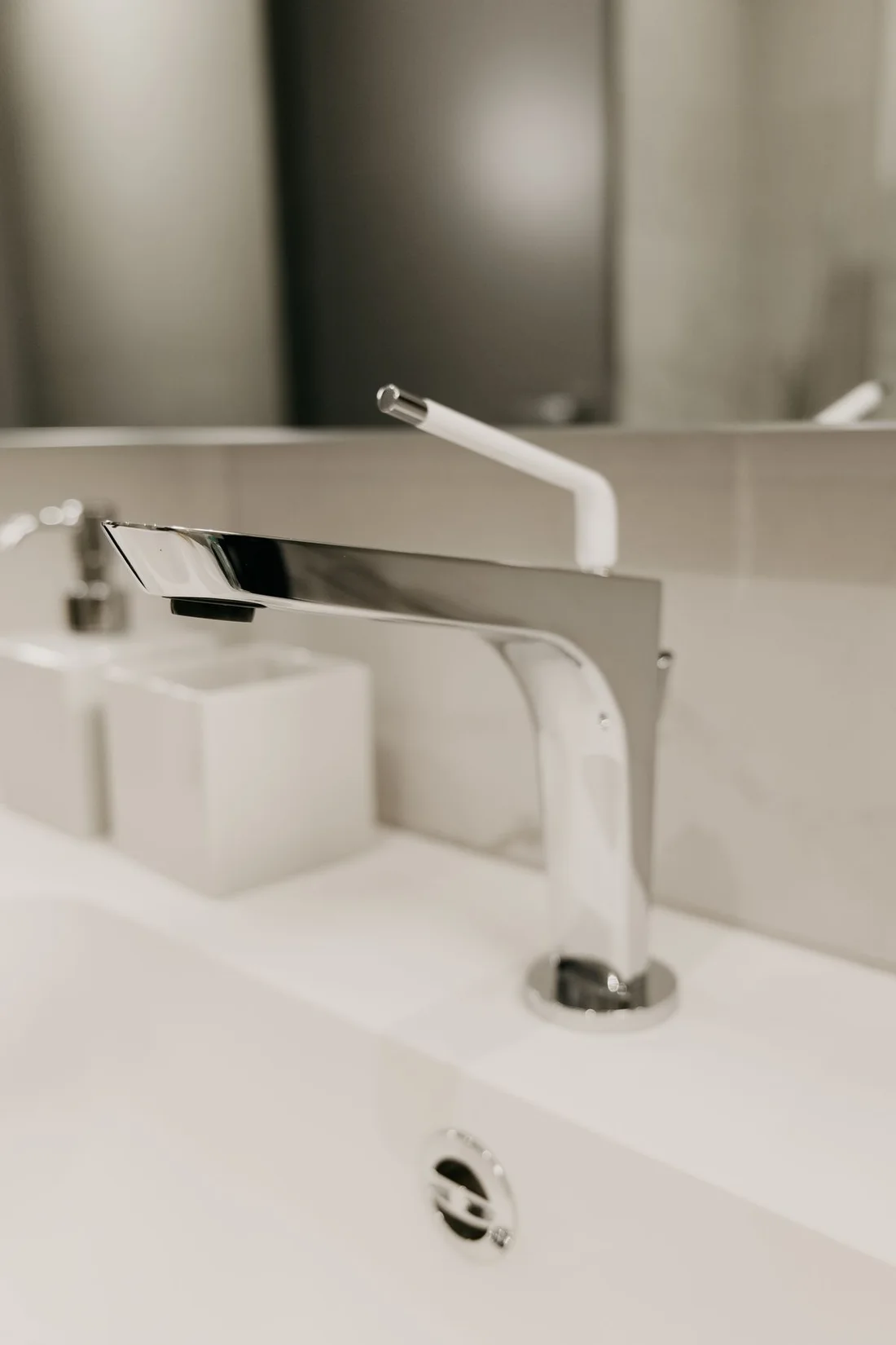 Close-up of a chrome basin faucet installed on a white ceramic sink
