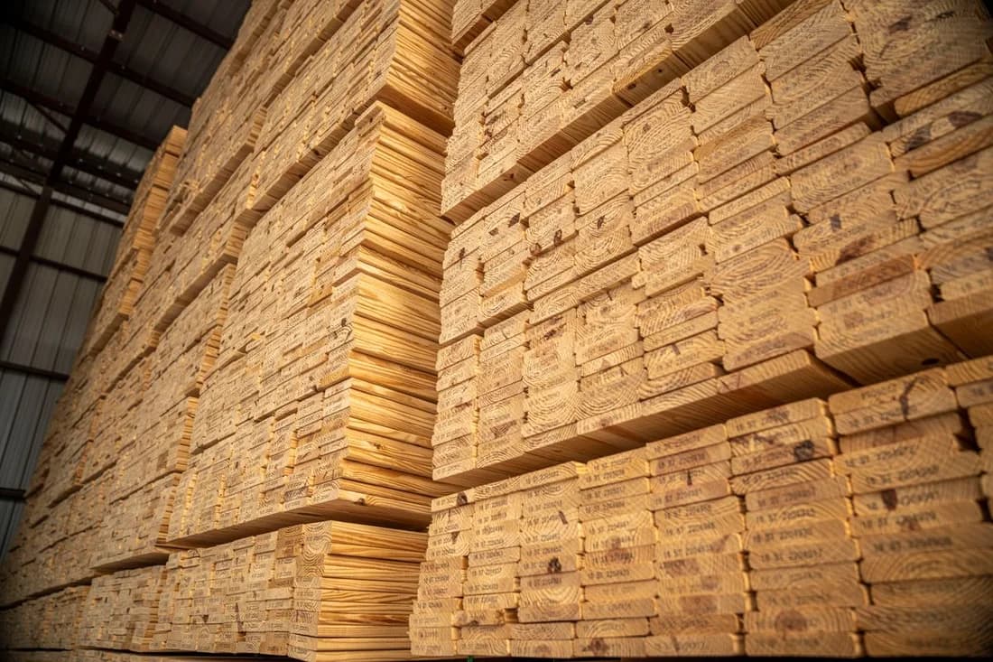 Stock photograph of large, neatly stacked timber bundles in indoor storage