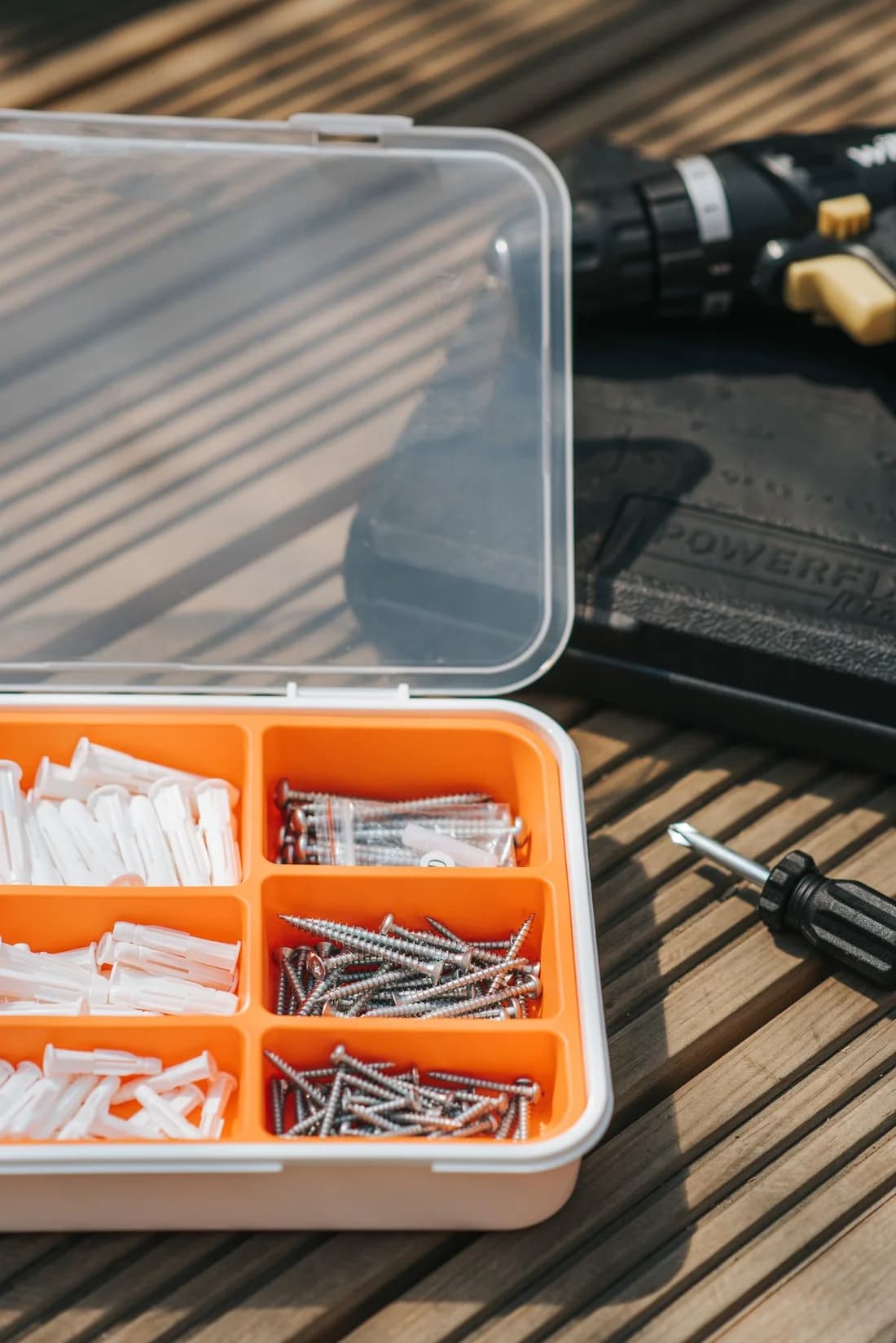 Real installation fixings in an orange organizer beside repair tools