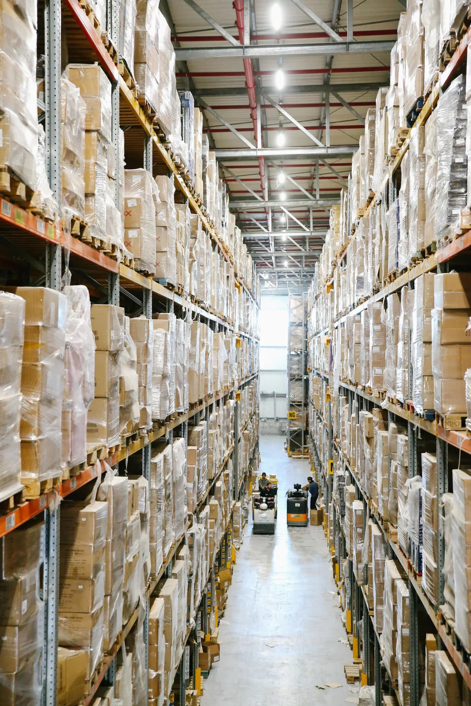 Stock photograph of modern warehouse aisles lined with neatly wrapped cartons on full storage racks